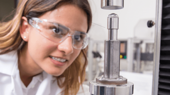 The glidewell advantage is innovation over 50 years. Woman Scientist looking at lab equipment with safety goggles