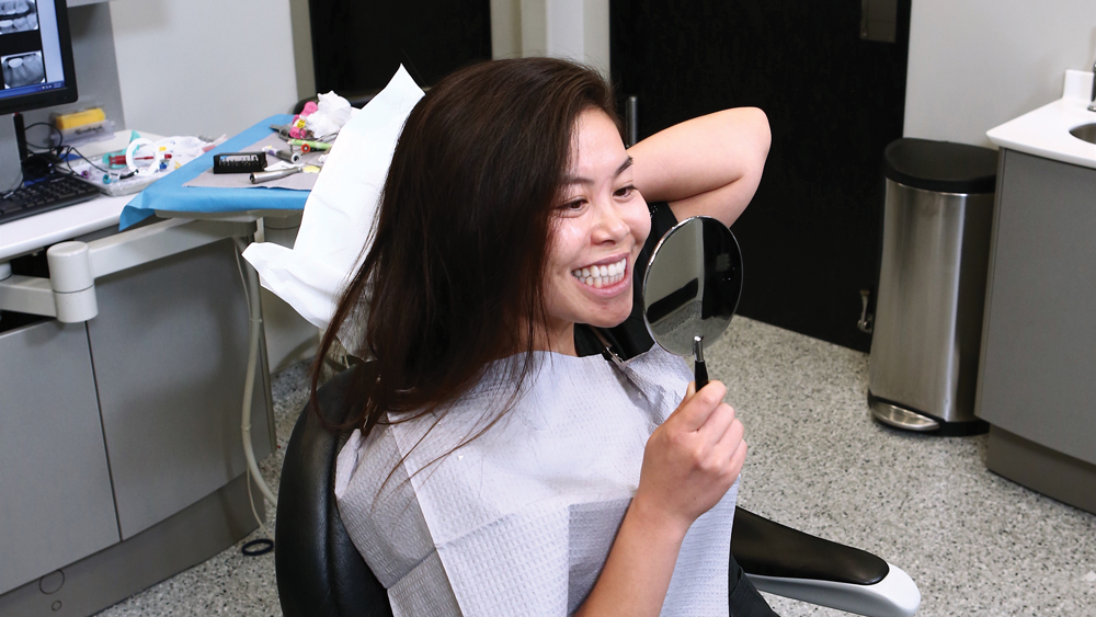 Patient viewing her teeth with handheld mirror