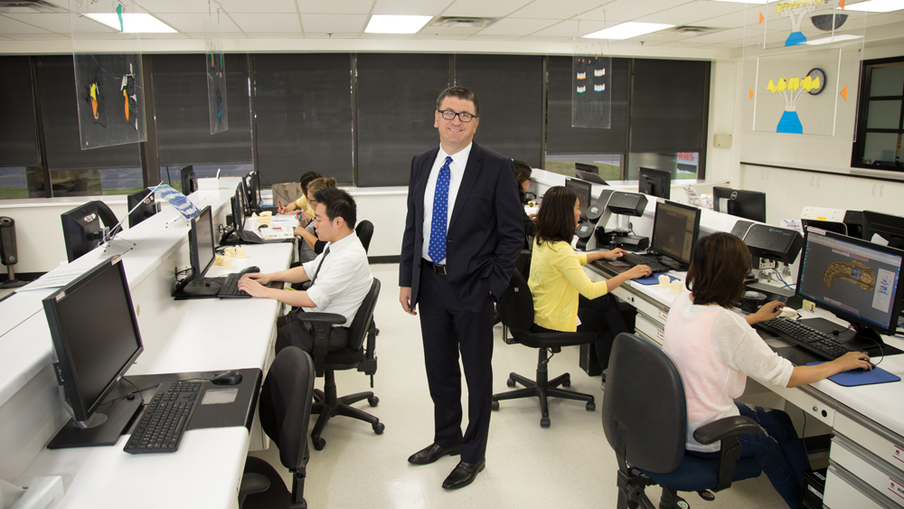 Joe standing in lab with technicians working around him