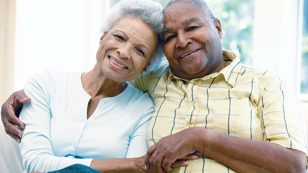 Older aged-couple sitting together, husband embracing wife