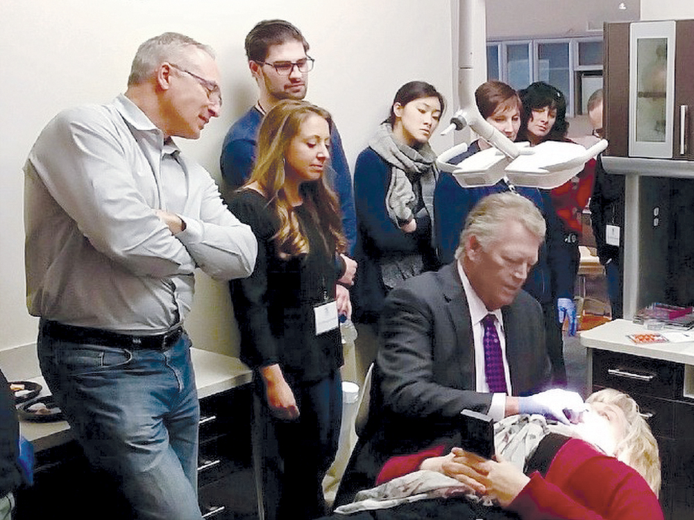 Team gathered around watching a demo of dr. and patient